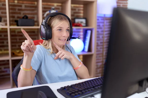 Young Caucasian Woman Playing Video Games Wearing Headphones Pointing Aside — Stock Photo, Image