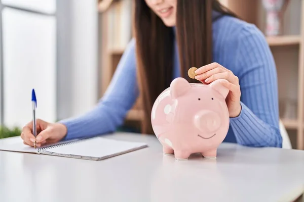 Chinese Woman Inserting Coin Piggy Bank Write Notebook Home — Stock Photo, Image