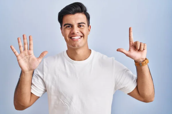 Hispánec Stojící Nad Modrým Pozadím Ukazující Ukazující Prsty Číslo Sedm — Stock fotografie