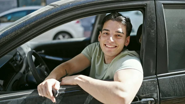 若いヒスパニック系の男が自信を持って路上で車の上に座って笑って — ストック写真