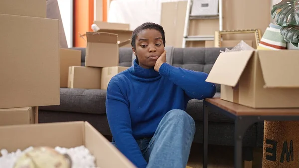 Stock image African american woman stressed sitting on floor at new home