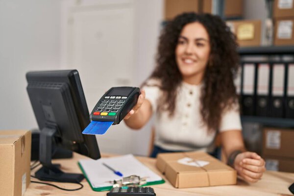 Young beautiful hispanic woman ecommerce business worker using data phone and credit card at office