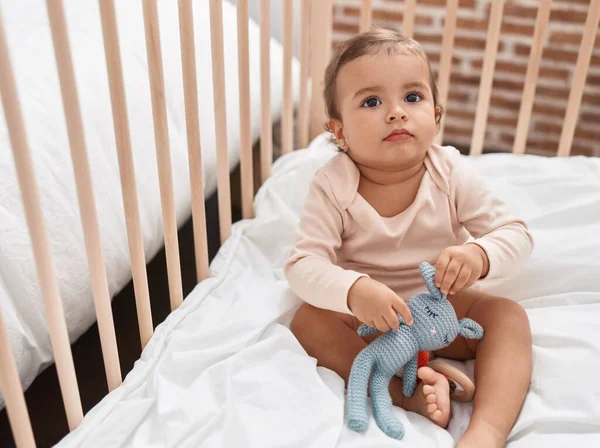 愛らしいHispanic赤ちゃん座っています上のクレイドル遊びとともにおもちゃでベッドルーム — ストック写真