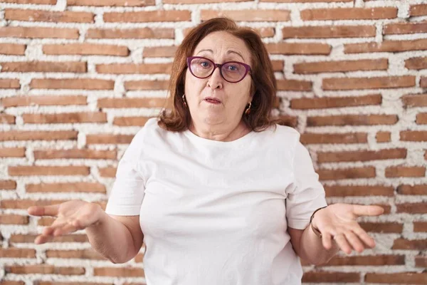 Senior Woman Glasses Standing Bricks Wall Clueless Confused Open Arms — Stock Photo, Image