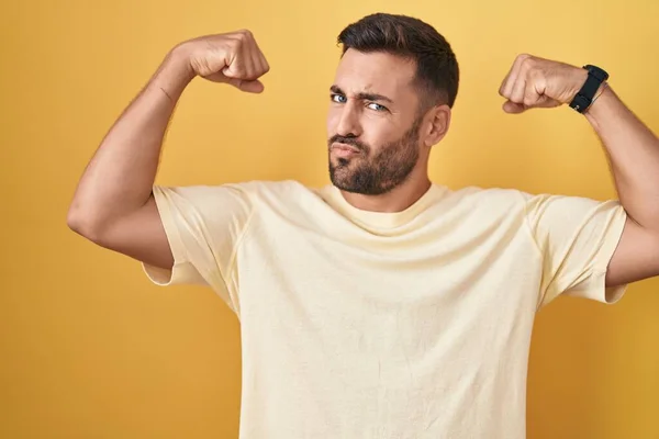 Snygg Latinamerikansk Man Står Över Gul Bakgrund Visar Armar Muskler — Stockfoto