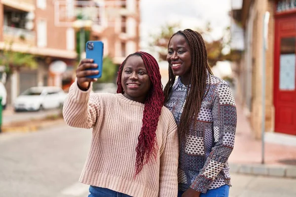 自信を持って笑顔でアフリカ系アメリカ人女性の友人作る自画自画自賛通りでスマートフォン — ストック写真