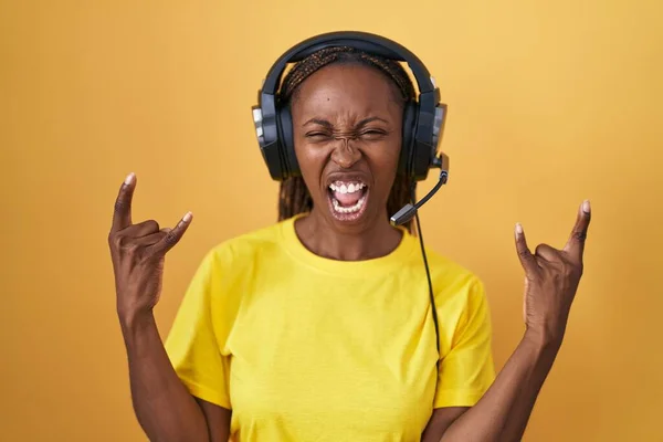 Mujer Afroamericana Escuchando Música Usando Auriculares Gritando Con Expresión Loca —  Fotos de Stock