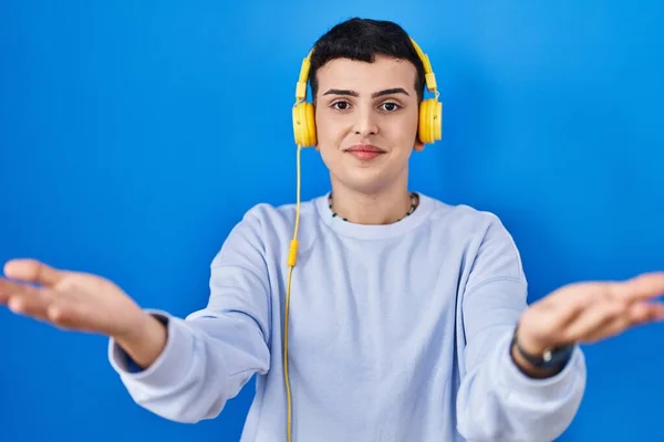 Niebinarna Osoba Słuchająca Muzyki Pomocą Słuchawek Uśmiechniętych Wesołych Rąk Oferujących — Zdjęcie stockowe