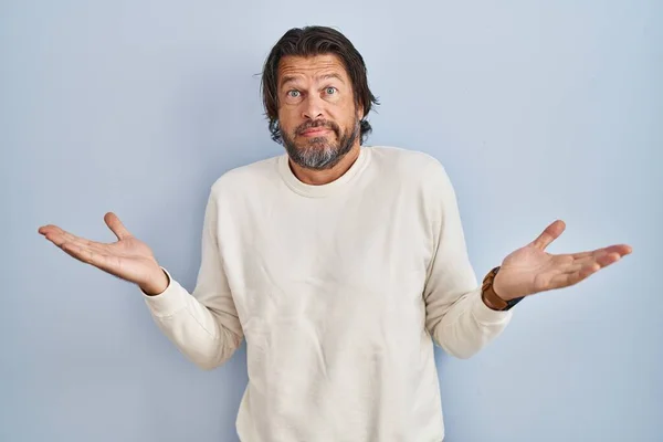 Schöner Mann Mittleren Alters Lässigem Pullover Über Blauem Hintergrund Ahnungslos — Stockfoto