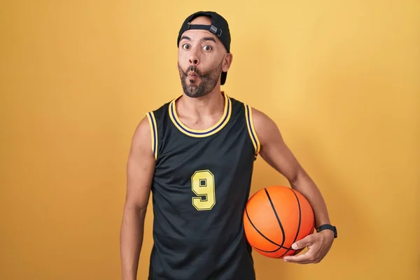 中年秃头男子拿着篮球盖在黄色的背景上 用嘴唇 疯狂和滑稽的姿势做鱼脸 有趣的表达方式 — 图库照片