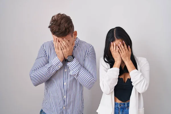 泣きながら手で顔を覆う悲しい表情で白い背景の上に立つ若いヒスパニック系のカップル うつ病の概念 — ストック写真
