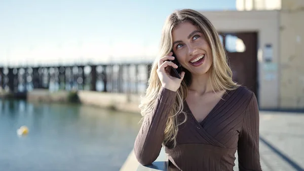 年轻的金发女人在海滨用智能手机自信地微笑着 — 图库照片