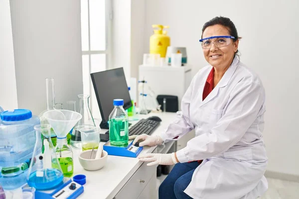 Middle Age Hispanic Woman Wearing Scientist Measuring Liquid Laboratory — стоковое фото