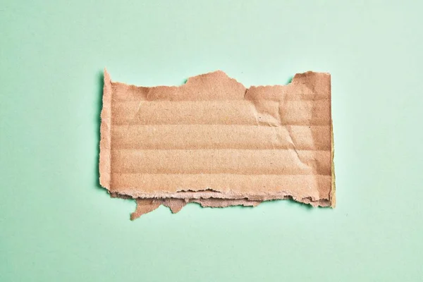 Ein Zerrissenes Stück Pappe Über Einem Isolierten Grünen Hintergrund — Stockfoto