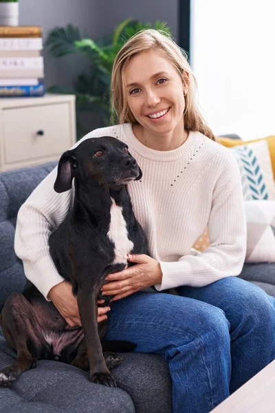 Young Blonde Woman Hugging Dog Sitting Sofa Home — Fotografia de Stock