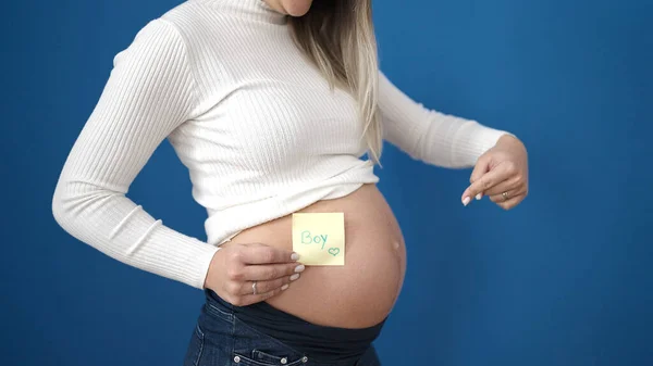 Молодая Беременная Женщина Указывает Мальчика Напоминание Бумаги Животе Изолированном Синем — стоковое фото