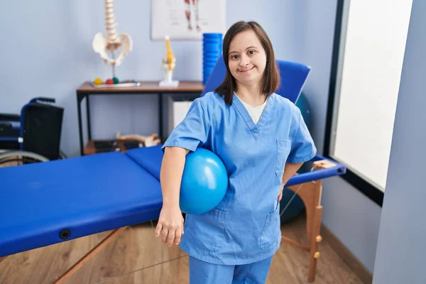ダウン症候群女性身に着けています理学療法制服保持ボールで理学療法士クリニック — ストック写真