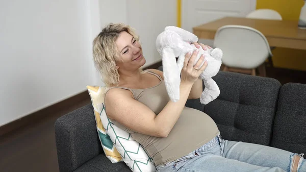 Evdeki Kanepede Elinde Oyuncak Bebek Tutan Hamile Bir Kadın — Stok fotoğraf