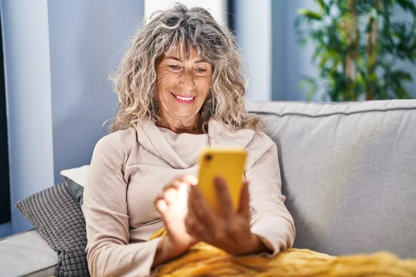 Frau Mittleren Alters Sitzt Mit Smartphone Hause Auf Sofa — Stockfoto