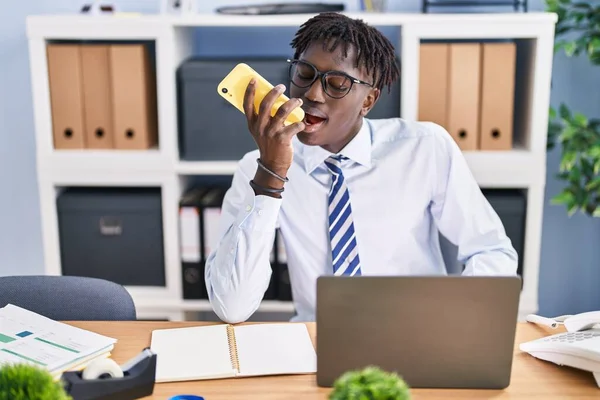 アフリカ系アメリカ人のサラリーマンがオフィスでスマートフォンで話すノートパソコンを使って — ストック写真