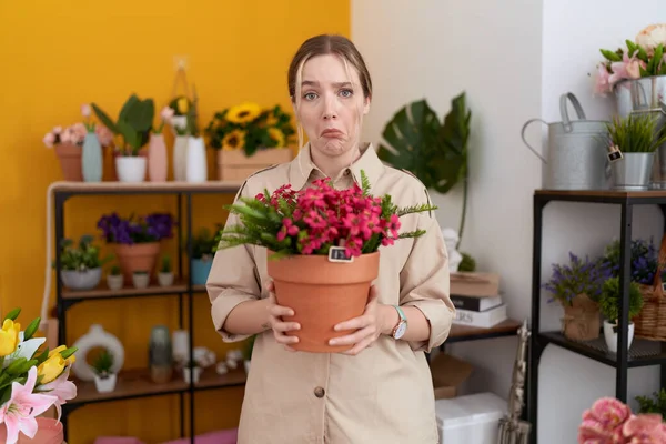 stock image Young caucasian woman working at florist shop holding plant pot depressed and worry for distress, crying angry and afraid. sad expression. 