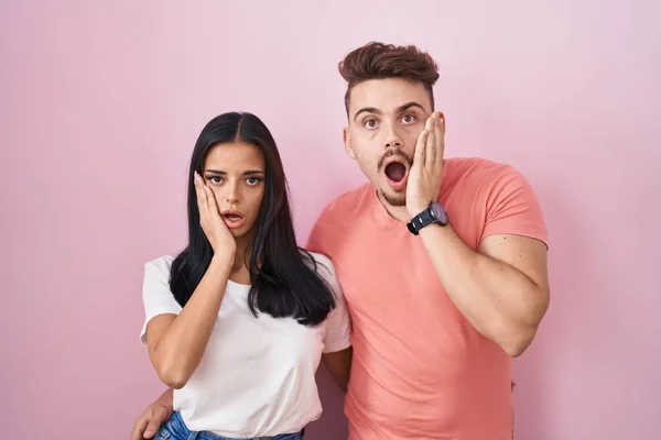 Young Hispanic Couple Standing Pink Background Afraid Shocked Surprise Amazed — Stockfoto