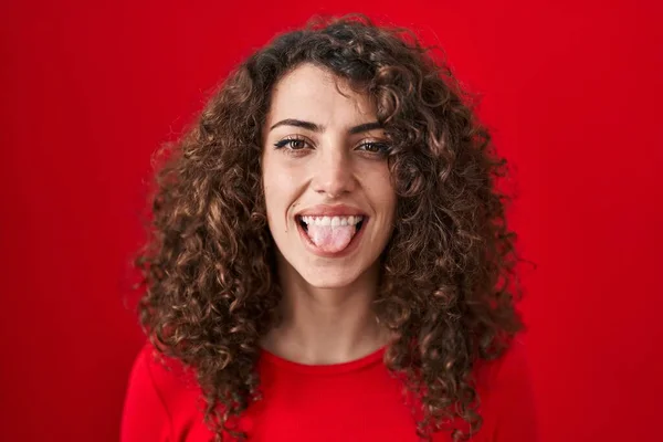 ヒスパニック女性あります巻き毛あります上の赤い背景ステッキング舌アウト幸せとともに面白い式 — ストック写真