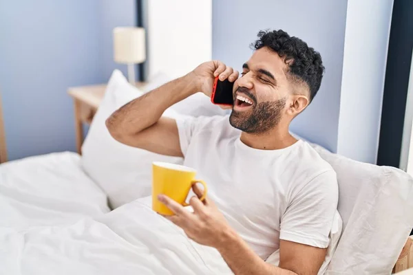 Hombre Hispano Joven Hablando Smartphone Tomando Café Sentado Cama Dormitorio — Foto de Stock