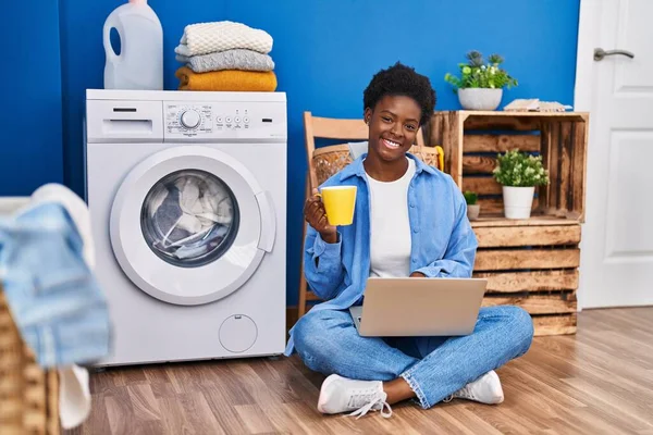 African American Woman Using Laptop Drinking Coffee Waiting Washing Machine —  Fotos de Stock