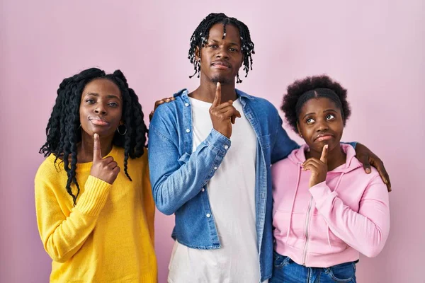 一组三个年轻的黑人站在粉红的背景上 满脑子疑惑 手指头放在下巴上 抬起头纳闷 — 图库照片