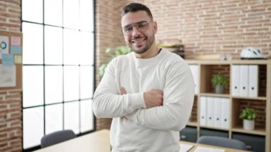 Genç İspanyol iş adamı ofiste kendinden emin gülümsüyor.