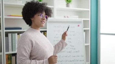 Genç Afrikalı Amerikalı kadın öğretmen üniversite sınıfında matematik dersi veriyor.