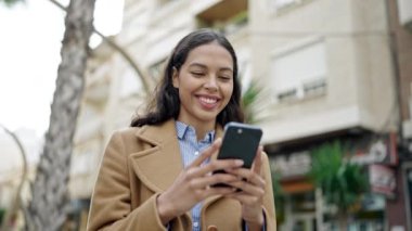 Sokakta gülümseyen akıllı telefon kullanan genç, güzel İspanyol kadın.