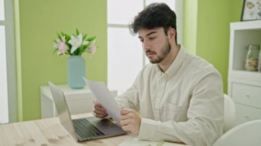 Genç İspanyol adam yemek odasında üzgün bir şekilde dizüstü bilgisayar okuyordu.
