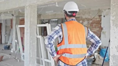 Orta yaşlı inşaatçı kendinden emin gülümsüyor inşaat alanında kollarını kavuşturmuş duruyor.