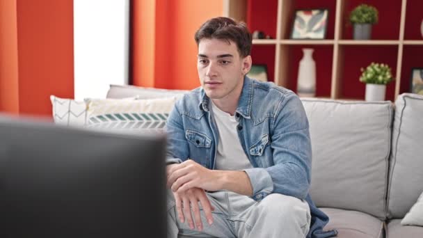 Молодий Іспаномовний Чоловік Дивиться Телевізор Сидячи Дивані Виразом Страху Вдома — стокове відео