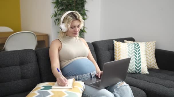 Молодая Беременная Женщина Используя Ноутбук Наушники Пишет Ноутбуке Учится Дома — стоковое видео