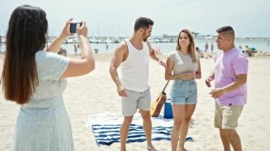 Sahilde akıllı telefondan dans eden bir grup insan video kaydediyor.