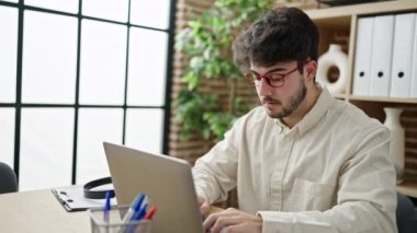 Genç İspanyol iş adamı ofiste görme problemi için dizüstü bilgisayar kullanıyor.