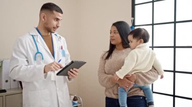 Çift ve oğlu klinikteki dokunmatik bloknotlara tıbbi danışmanlık yapıyorlar.