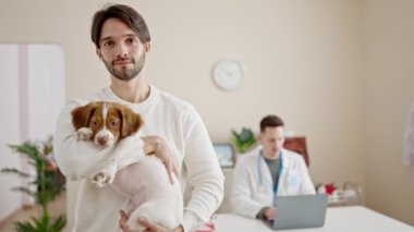 Veteriner kliniğinde dizüstü bilgisayar kullanan iki adam.