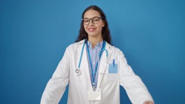 Güzel İspanyol kadın doktor, izole edilmiş mavi arkaplanı onaylıyor.