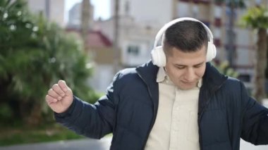 Genç İspanyol adam parkta müzik dinliyor ve dans ediyor.