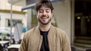 Kahve dükkanının terasında kendinden emin gülümseyen genç İspanyol adam.