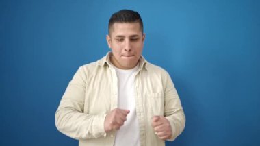 Genç İspanyol adam gülümsüyor mavi arka planda dans ediyor.