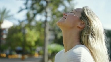 Young blonde woman smiling confident breathing at park