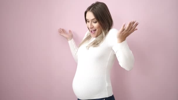 Молодая Беременная Женщина Трогает Живот Удивленный Изолированном Розовом Фоне — стоковое видео