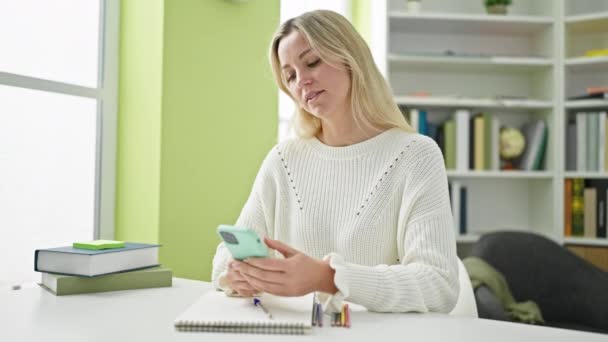 Junge Blonde Studentin Nutzt Smartphone Bibliothek — Stockvideo