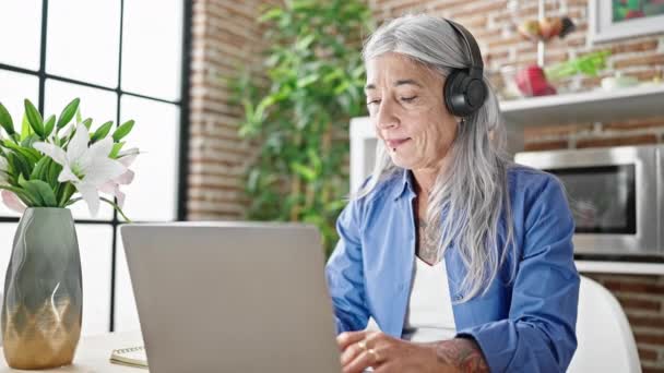 Kobieta Średnim Wieku Siwymi Włosami Korzystająca Laptopa Słuchawek Jadalni — Wideo stockowe