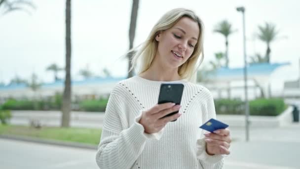 年轻的金发女人在街上买智能手机和信用卡 — 图库视频影像